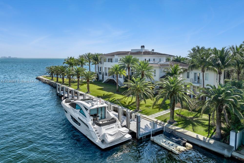 Yacht docked in front of luxury waterfront mansion